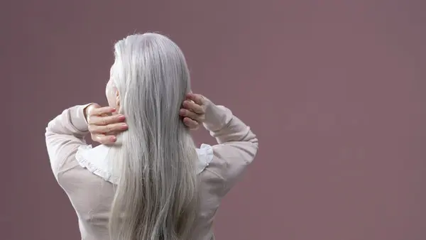 Mulher de costas com cabelo grisalho longo — menopausa e ciclo do cabelo