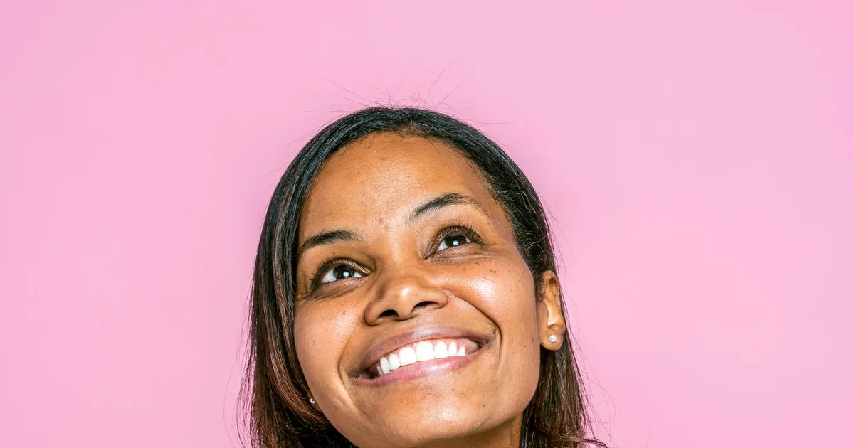 Mulher na faixa dos 40 anos sorrindo — sinais da perimenopausa no cabelo