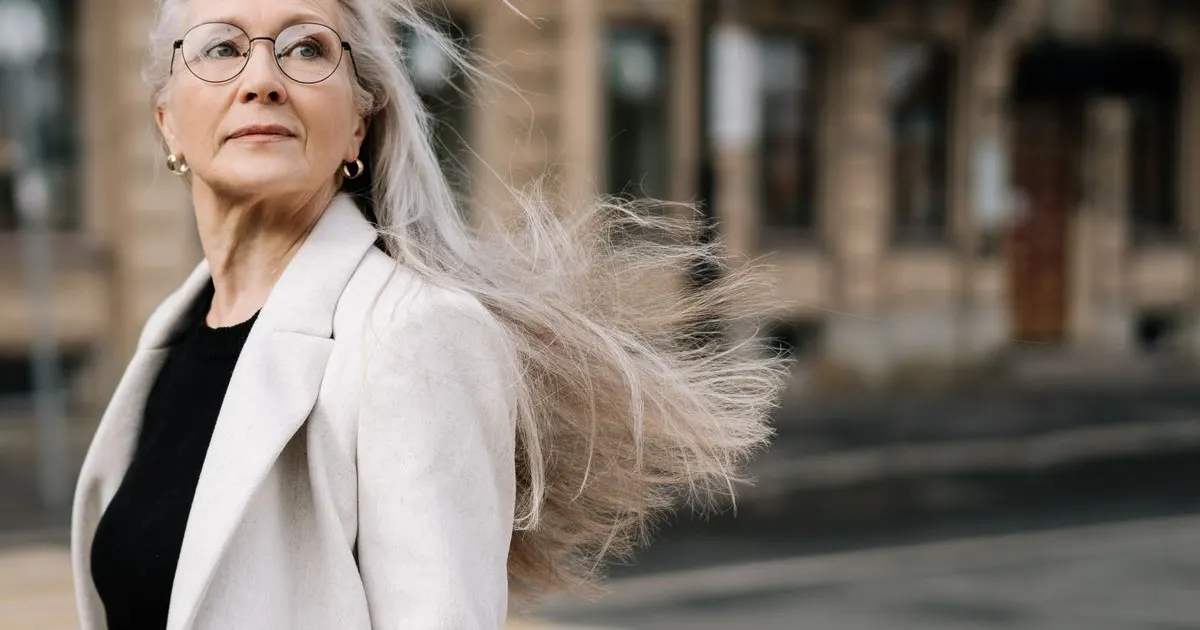 Mulher madura de óculos com cabelo grisalho longo ao vento — cabelo fino depois dos 40