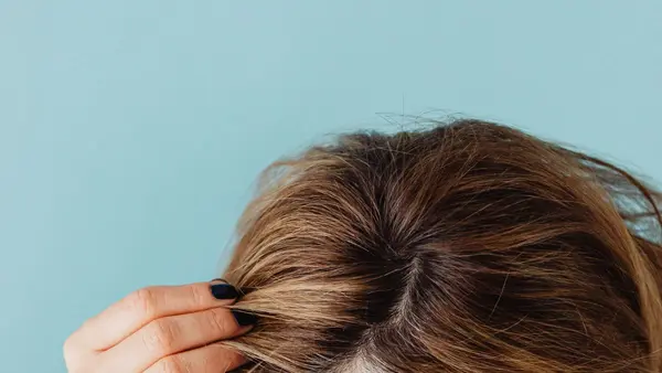 Mulher separando os fios de cabelo pra examinar a raiz — artigo sobre canetas emagrecedoras e queda de cabelo