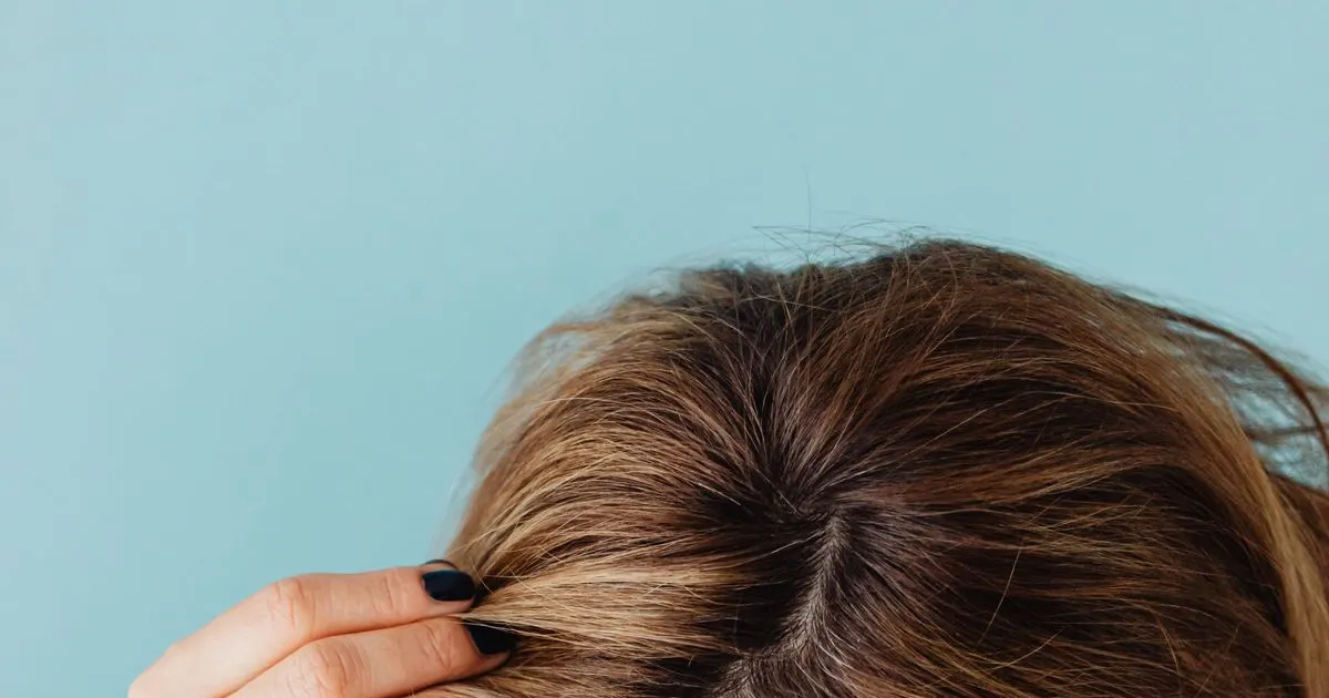 Mulher separando os fios de cabelo pra examinar a raiz — imagem ilustrativa do artigo sobre canetas emagrecedoras e queda de cabelo