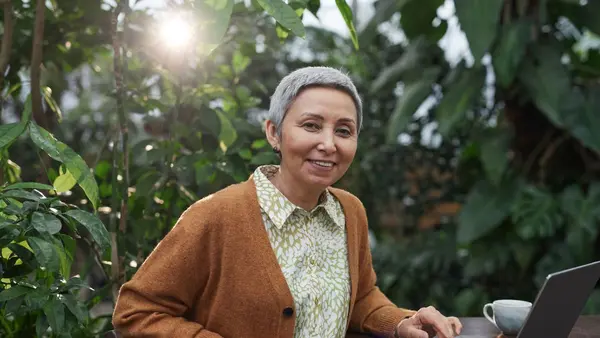 Mulher madura sorridente, cabelo grisalho curto, organizando sua rotina — artigo sobre a rotina de 30 dias contra a queda de cabelo